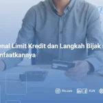 Seorang pria memegang kartu kredit sambil mencatat pengeluaran di meja kerja